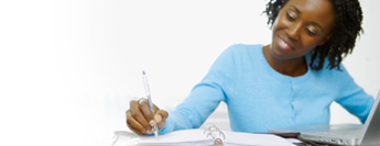 Photograph of woman writing at desk.