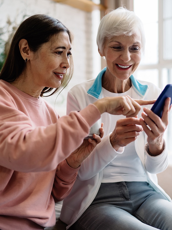 Image of two women reviewing prescriptions on a cell phone