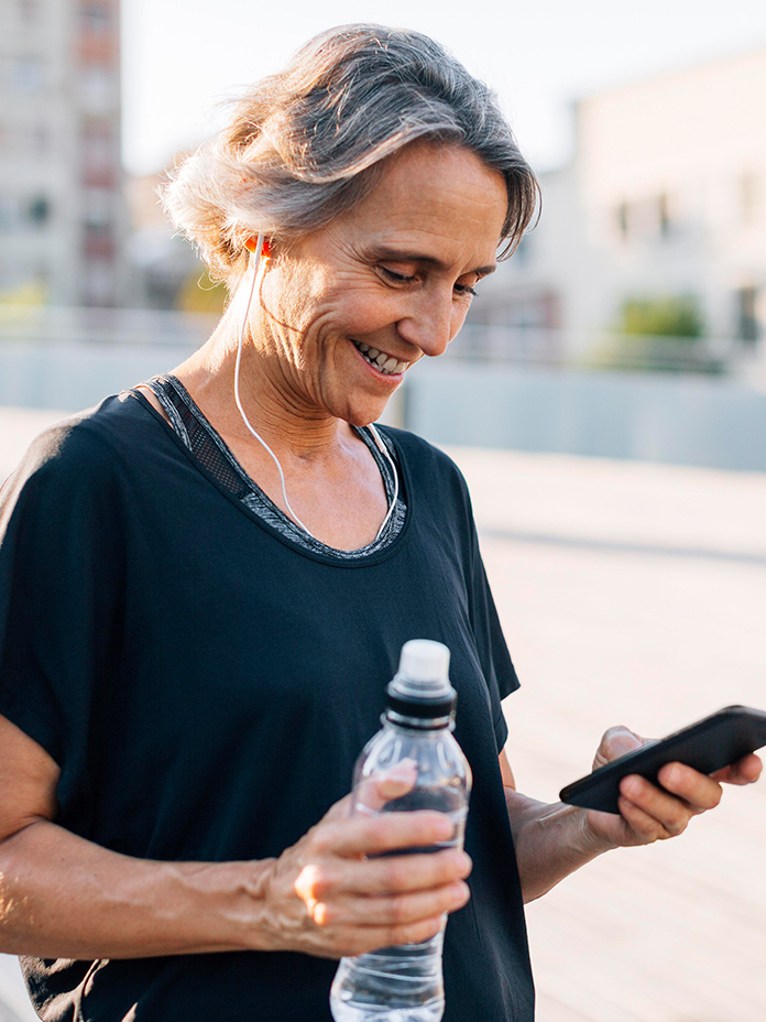 a woman on her run looking at her phone, using her online healthcare benefit