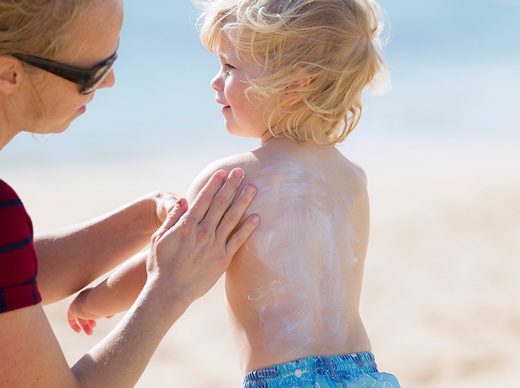 Mother rubbing sunscreen on daughter
