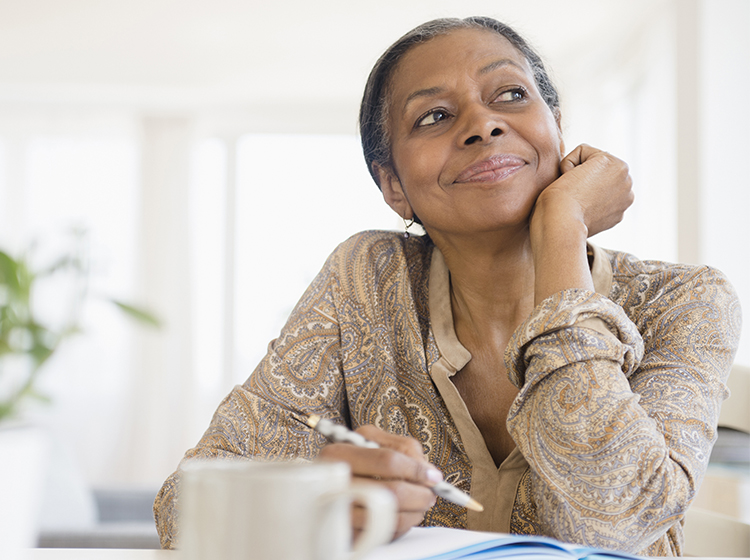 Woman sitting inside holding a pen