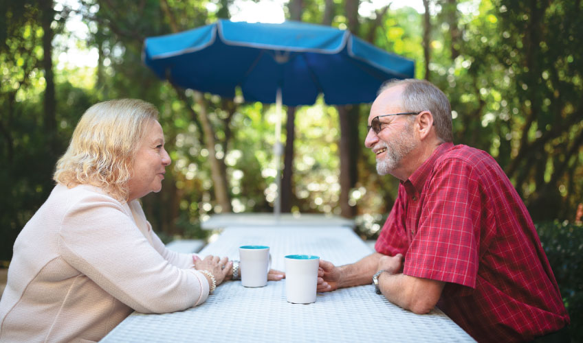 two older individuals discussing Medicare information over coffee