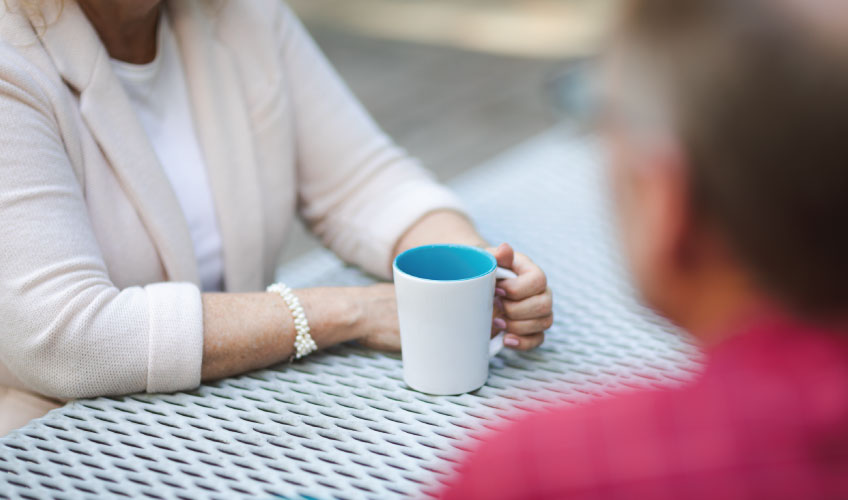 Two people discussing Medicare information over coffee