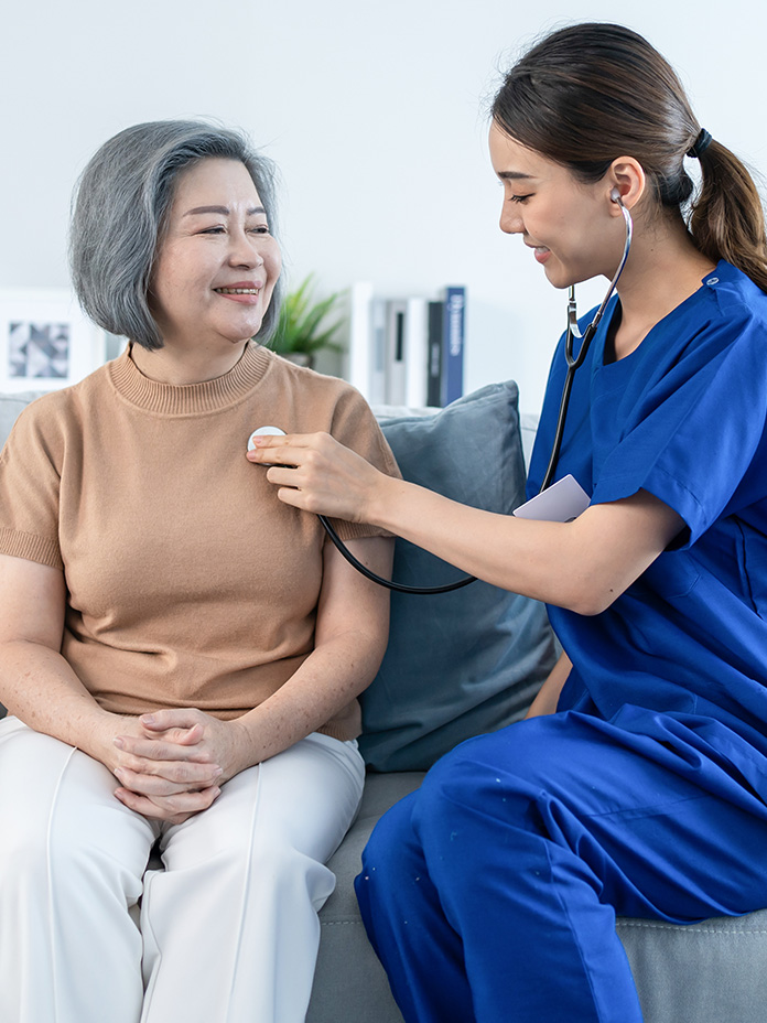 Image of a nurse using a stethoscope to check an elderly woman's heart rate during a Healthy home visit.