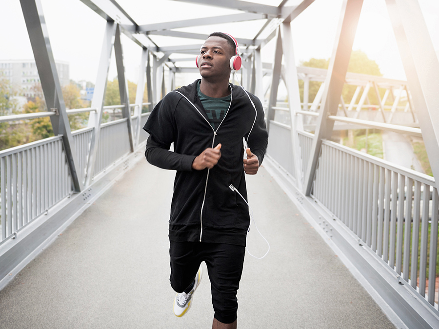 Young man running outdoors, wearing headphones