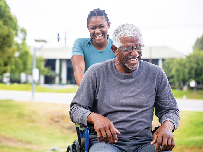 Image of a smiling girl pushing an elderly man on a wheelchair provided by DME coverage